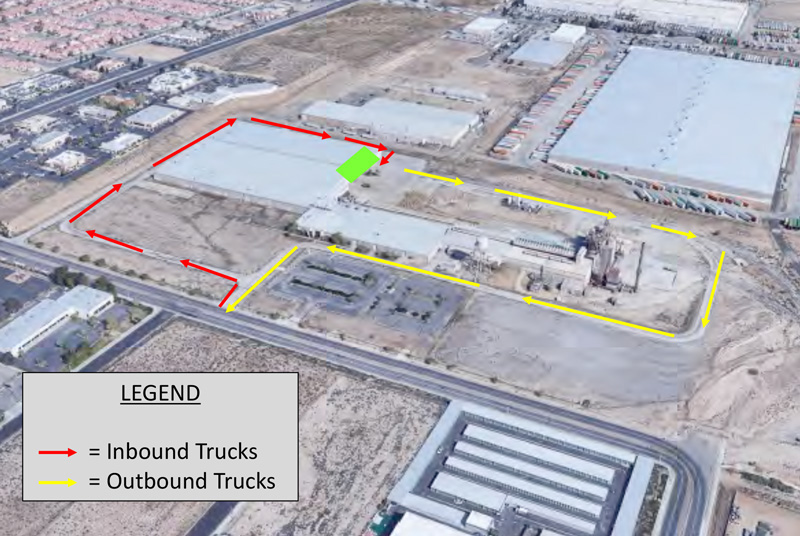 Aerial view of an industrial facility with red arrows showing the route for inbound trucks and yellow arrows showing the route for outbound trucks. A green area and a legend explaining the arrows are also visible.
